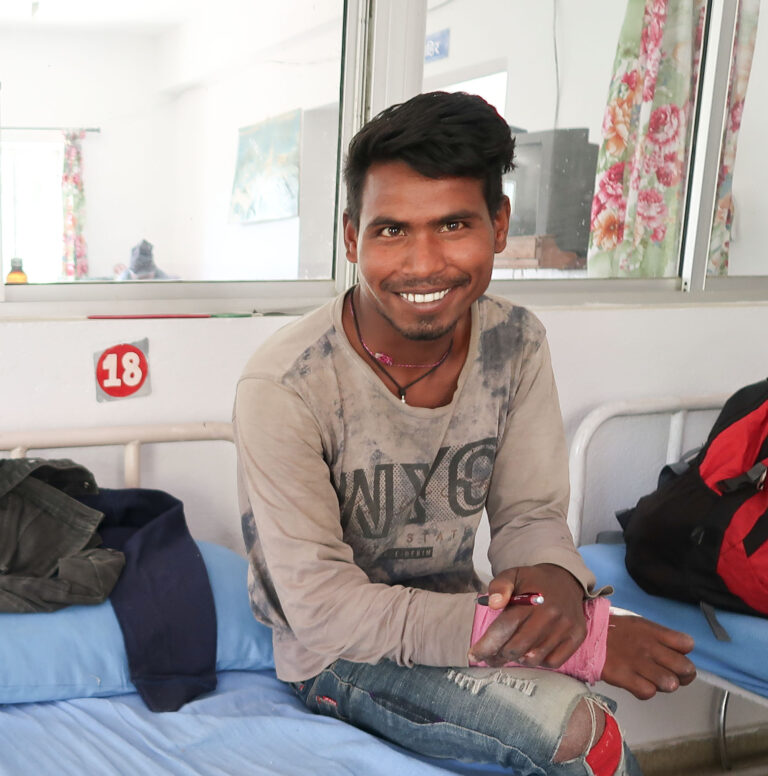 Bijay, ein junger Nepali sitzt auf einem Spitalbett. Seine Hand ist in einem Verband eingebunden.