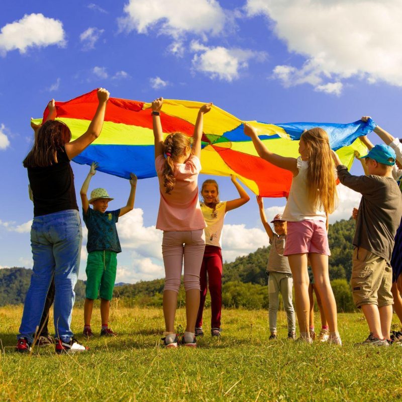 Kinder spielen mit einem Falschirm draussen